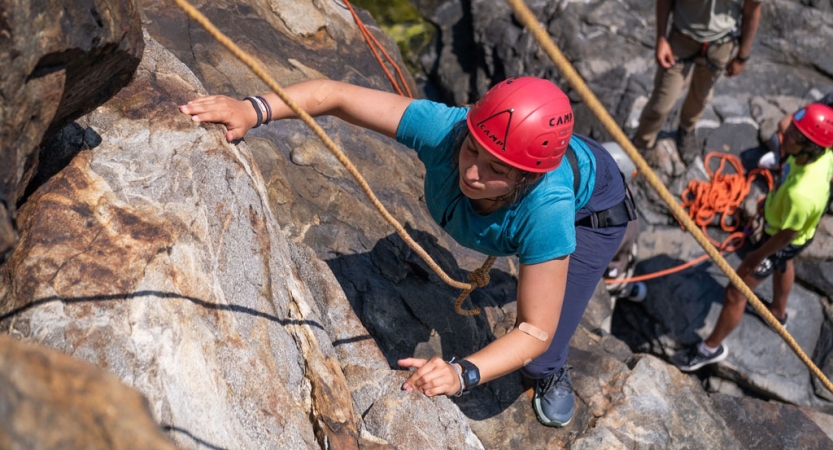 A person wearing safety gear is attached to ropes as they climb up toward the camera. 
